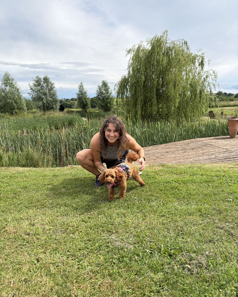 Hannah crouching in a field with Maple